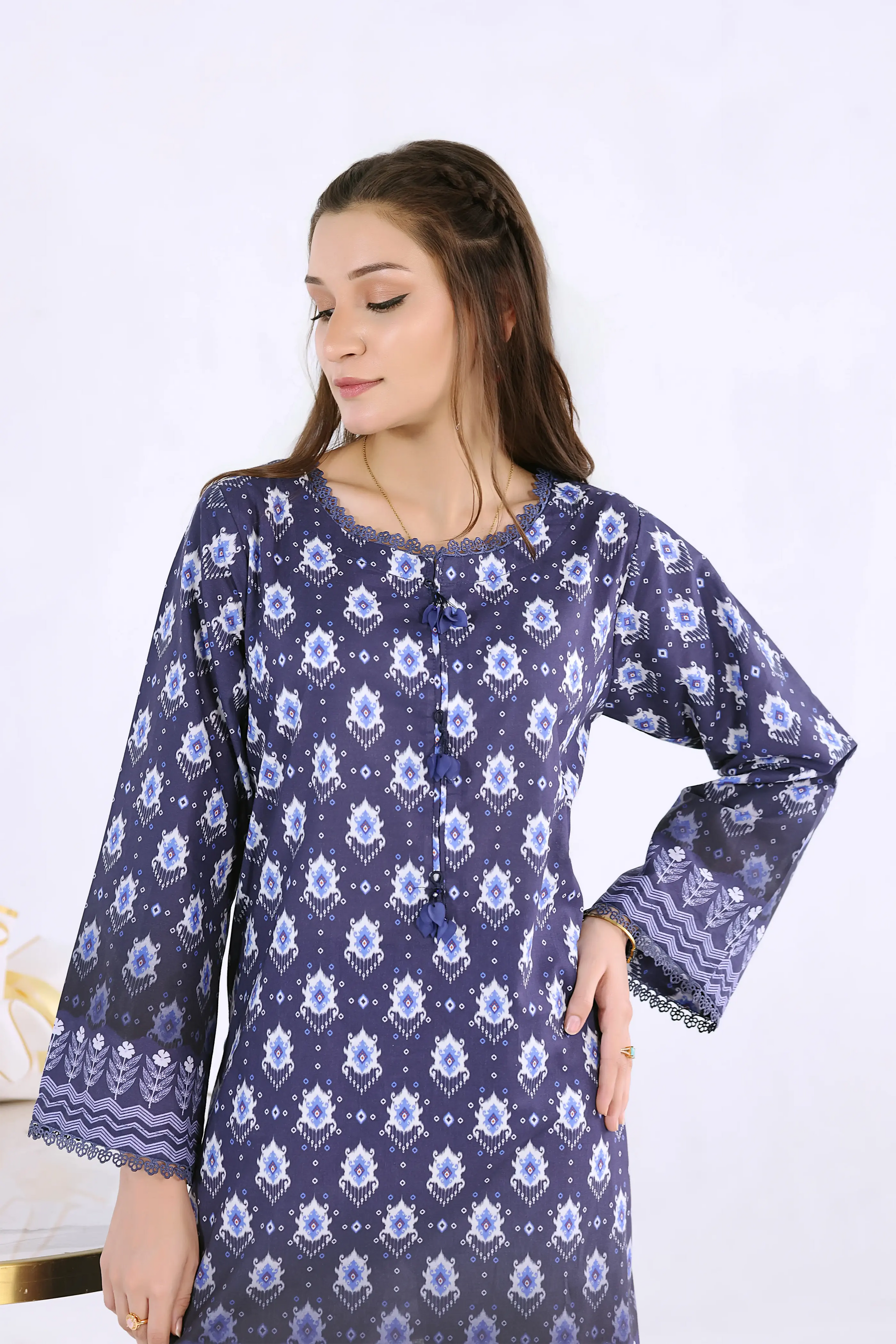 Close-up of digital print shirt featuring tassel accents and delicate lace on the round neckline.