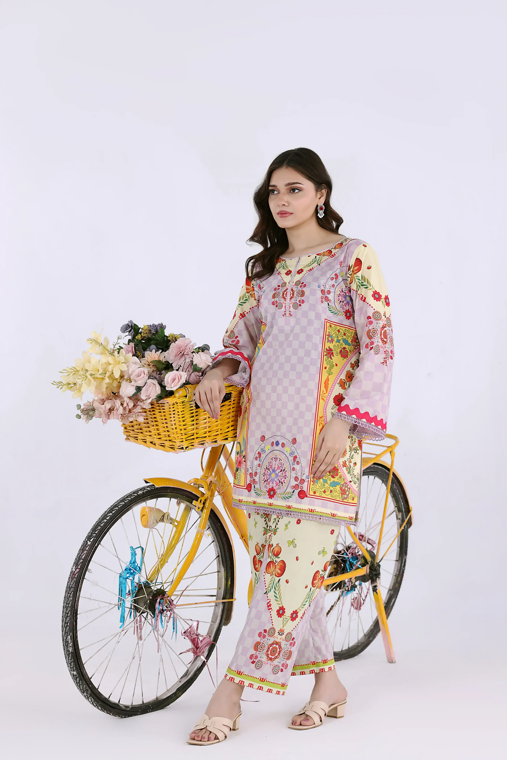 Standing view of a premium checkered lawn co-ord set with a yellow prop bicycle, perfect for a fresh summer look.